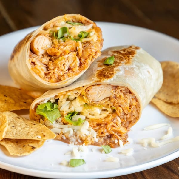 Two halves of a Crazy King Burrito, filled with chicken, rice, cheese, and lettuce, served with tortilla chips.